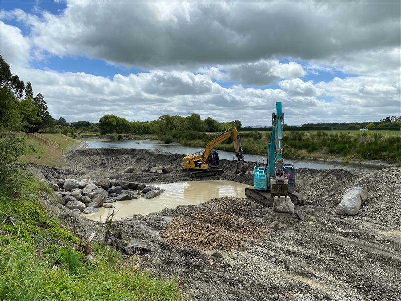 Two diggers working on the bank of the Ruamāhanga River