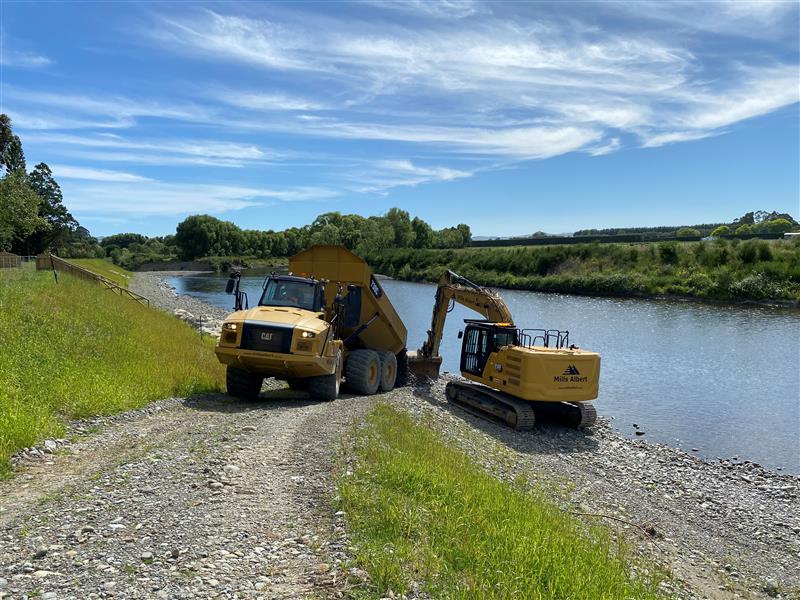 A digger and a tipper truck on the bank of the Ruamāhanga River