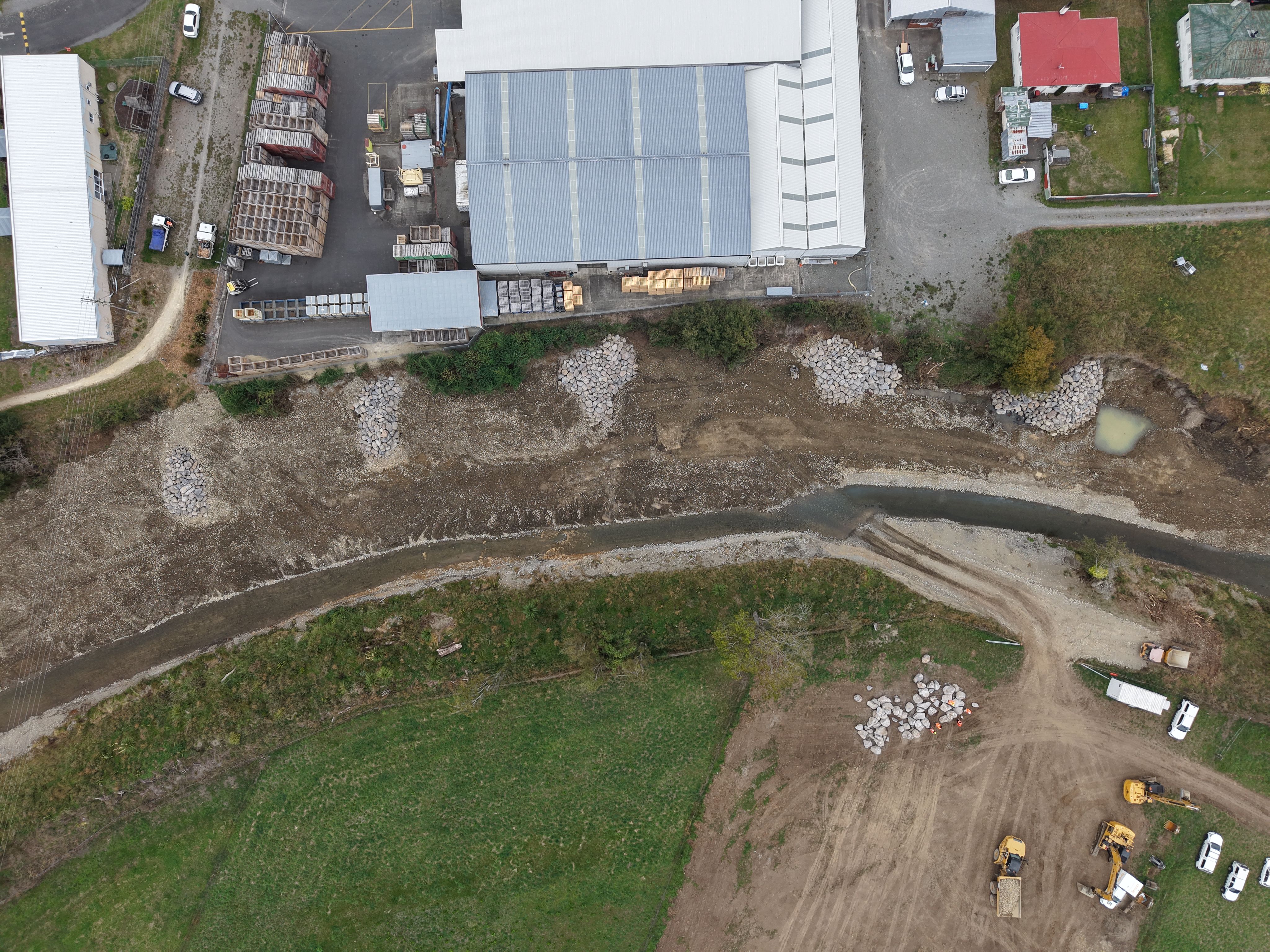 An aerial view of the Waipōua River where it cuts close to an industrial site