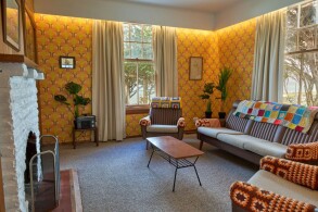 The lounge of the Lightkeeper's Cottage; a warm-coloured room with a lounge suite and coffee table