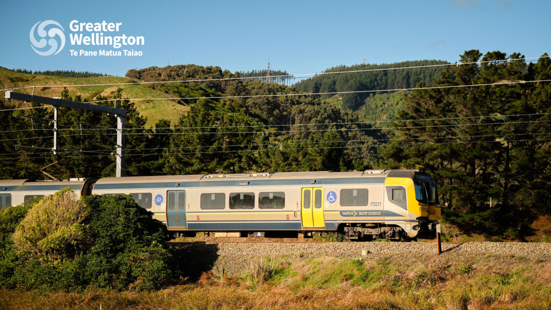 A train on the Kāpiti Line with picturesque hills in the background