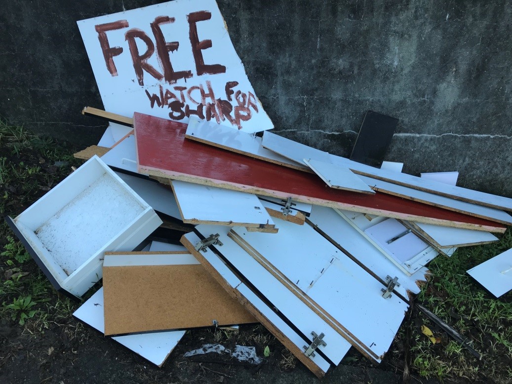 A pile of treated timber including drawers and cupboard doors, and a handwritten sign saying 'Free - watch for sharp'