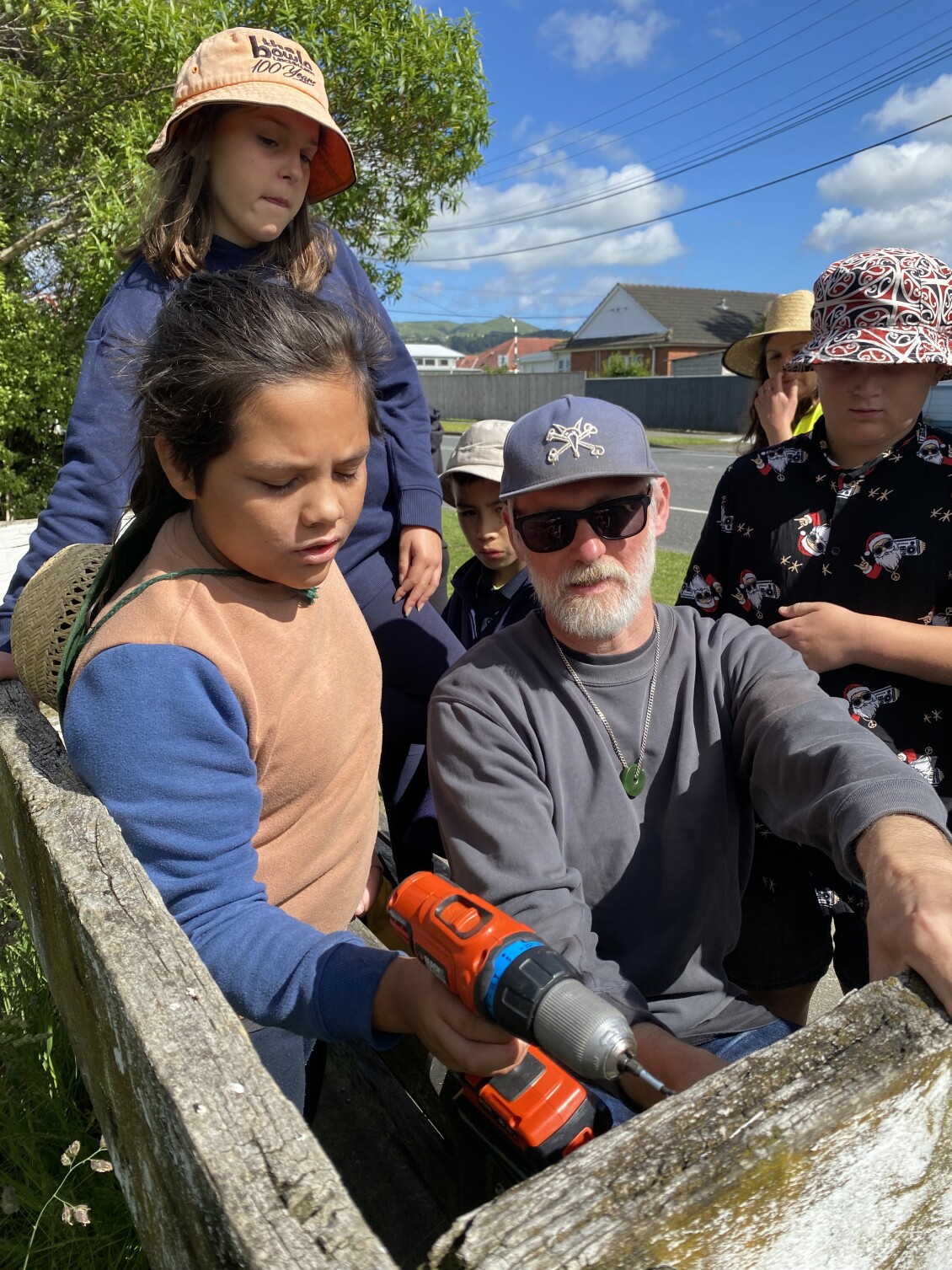 A Naenae Primary School teacher helps a student screw their "Do not harm tuna" sign to a fence
