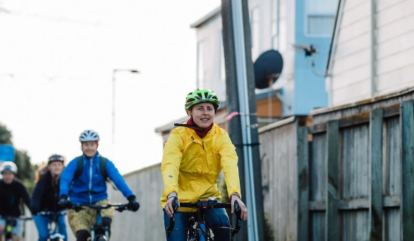 A row of cyclists bike down a city footpath